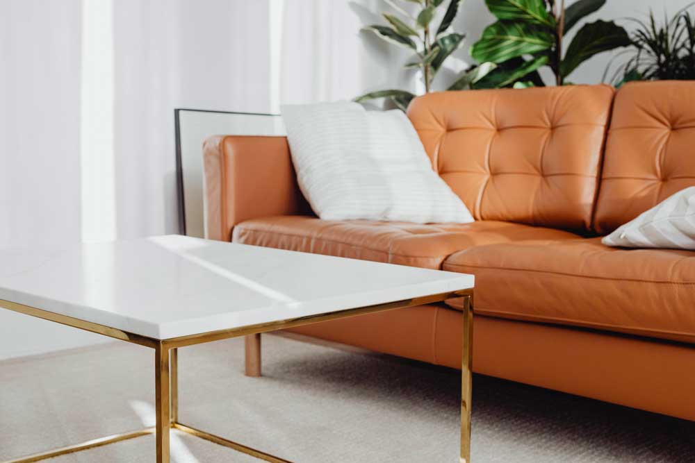 Canapé en cuir marron avec table basse blanche et en métal doré