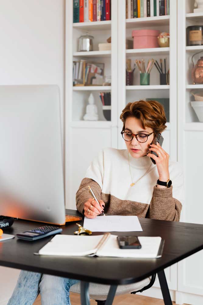 Femme assise à son bureau et au téléphone